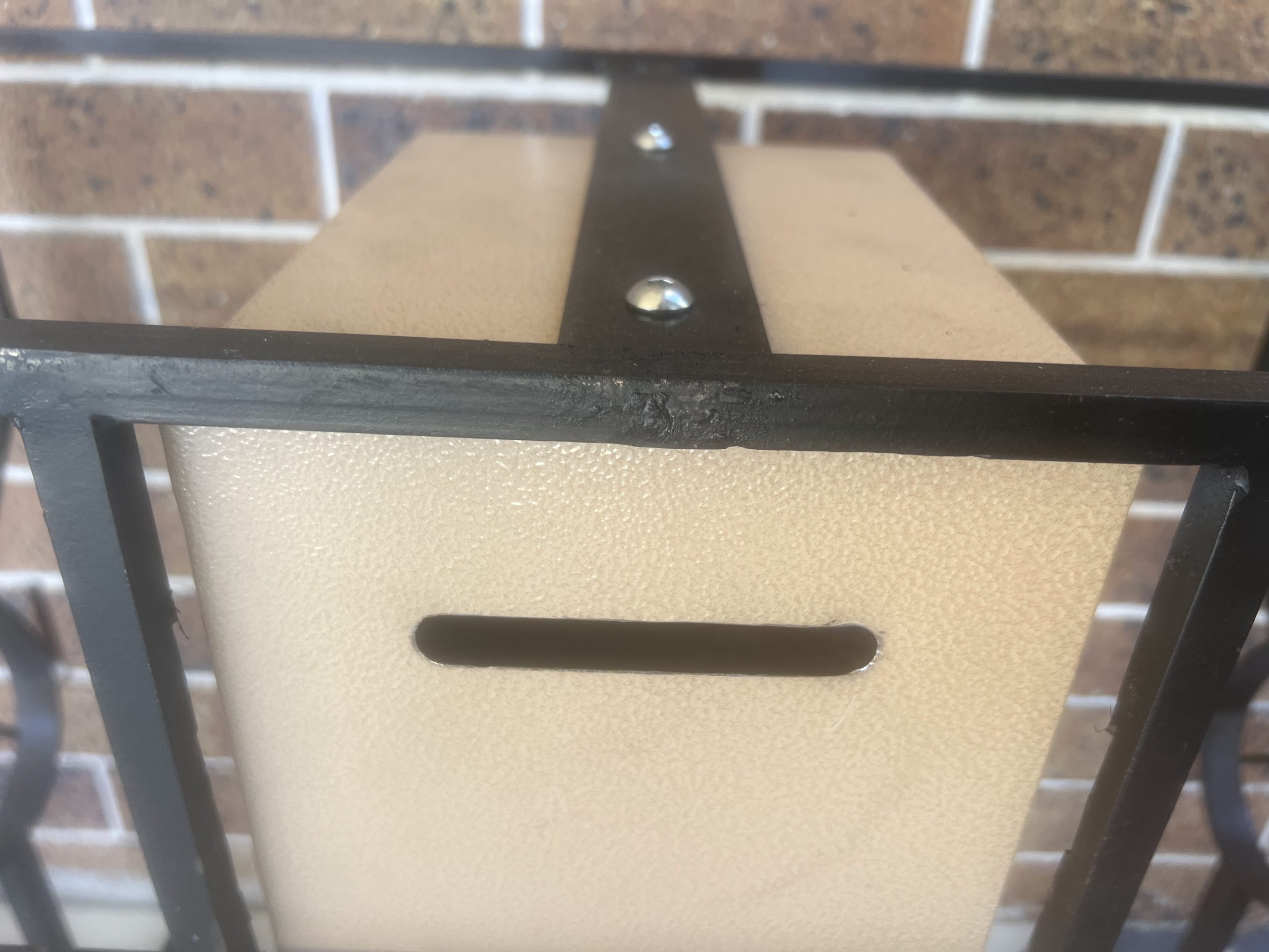 Locking safe-style money box in the wrought steel base of a votive candle stand